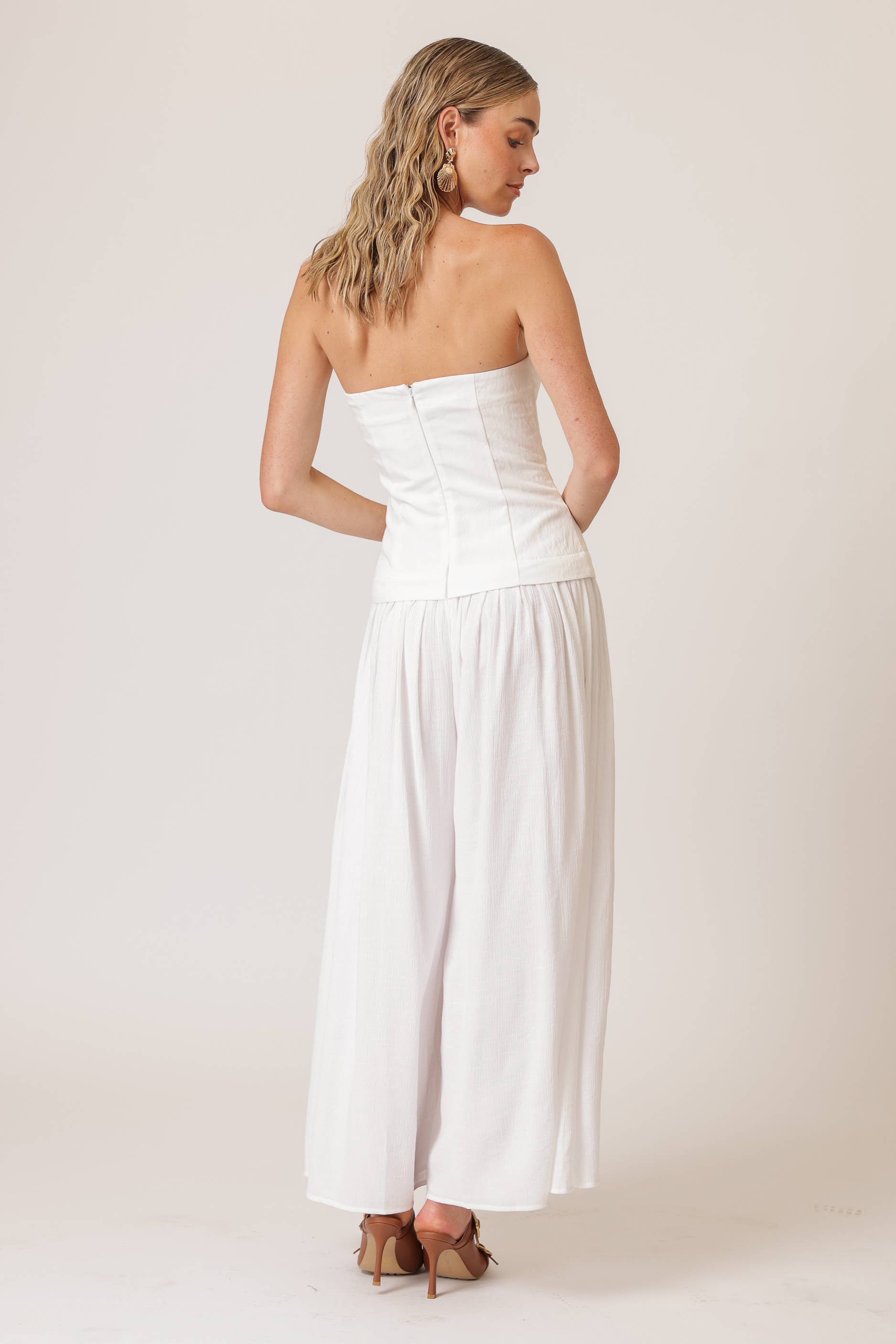 Women’s boutique clothing; Theo white jumpsuit with strapless neckline, wide-leg pants; perfect for summer collection boutique.