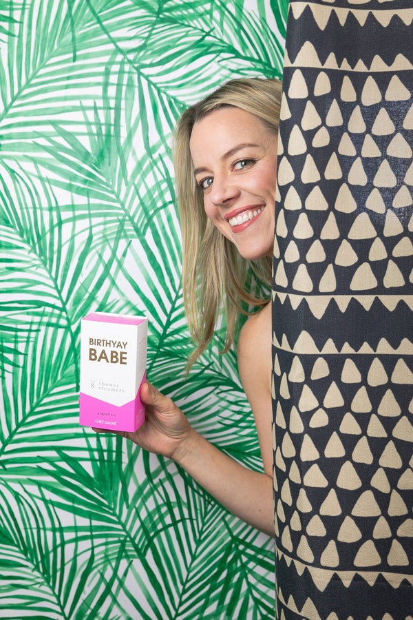 Woman holding Birthyay Babe birthday shower steamers in vibrant bathroom setting, perfect for a refreshing birthday celebration.