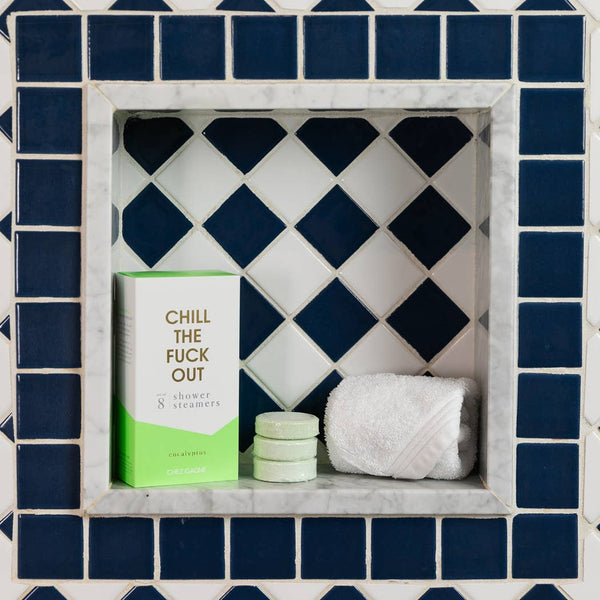 Chill the Fuck Out Eucalyptus Shower Steamers set displayed with cotton towel in a stylish bathroom niche.