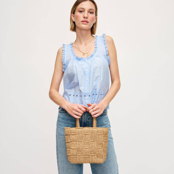 Model wearing a light blue ruffled top paired with denim, holding a chic woven handbag, perfect for summer outings.