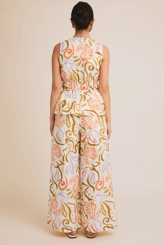 Elegant women's boutique clothing set featuring a sleeveless V-neck top and wide-leg pants in pastel abstract floral print.