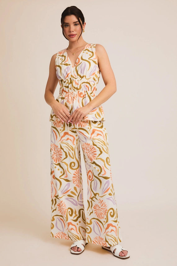 V-neck sleeveless ruffle hem top with wide leg pants in vibrant abstract print. Perfect for summer collection boutique.