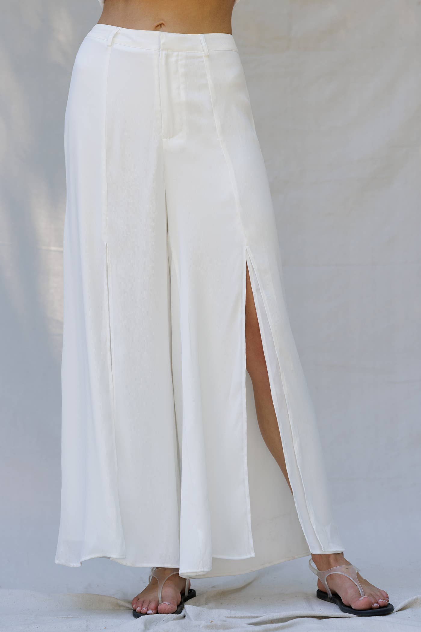 Sleek white wide-leg pants with side slits, perfect for resort wear, summer events, and women's boutique clothing.