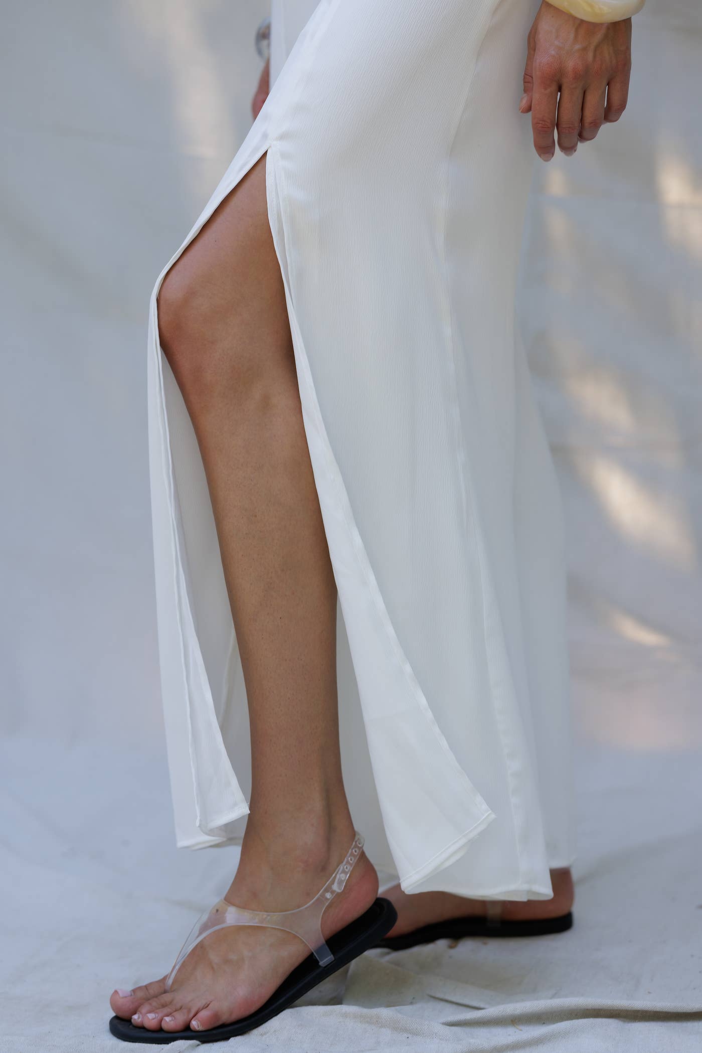 Detail of model's leg in elegant white two-piece set, perfect for warm weather, from women's boutique clothing collection.