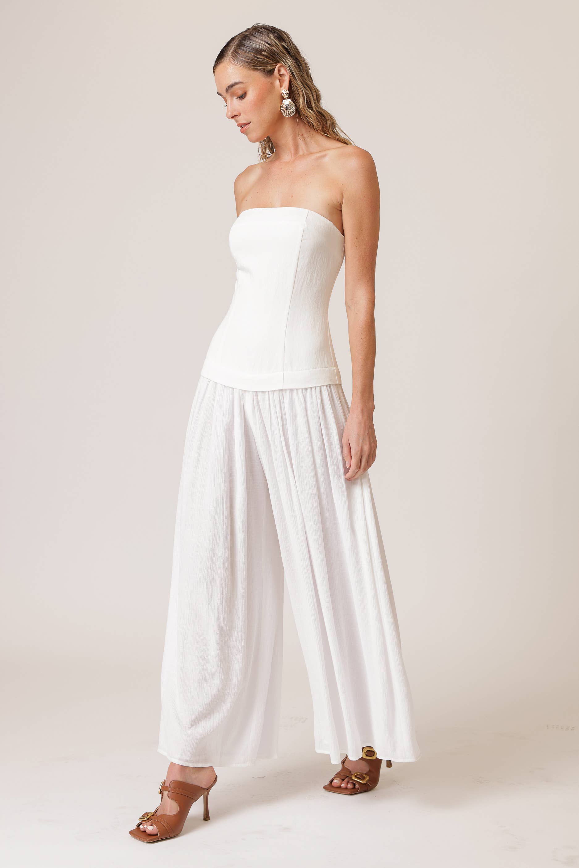 Model wearing a chic strapless white jumpsuit, perfect for women's boutique clothing and summer collection. New arrivals for 2023.