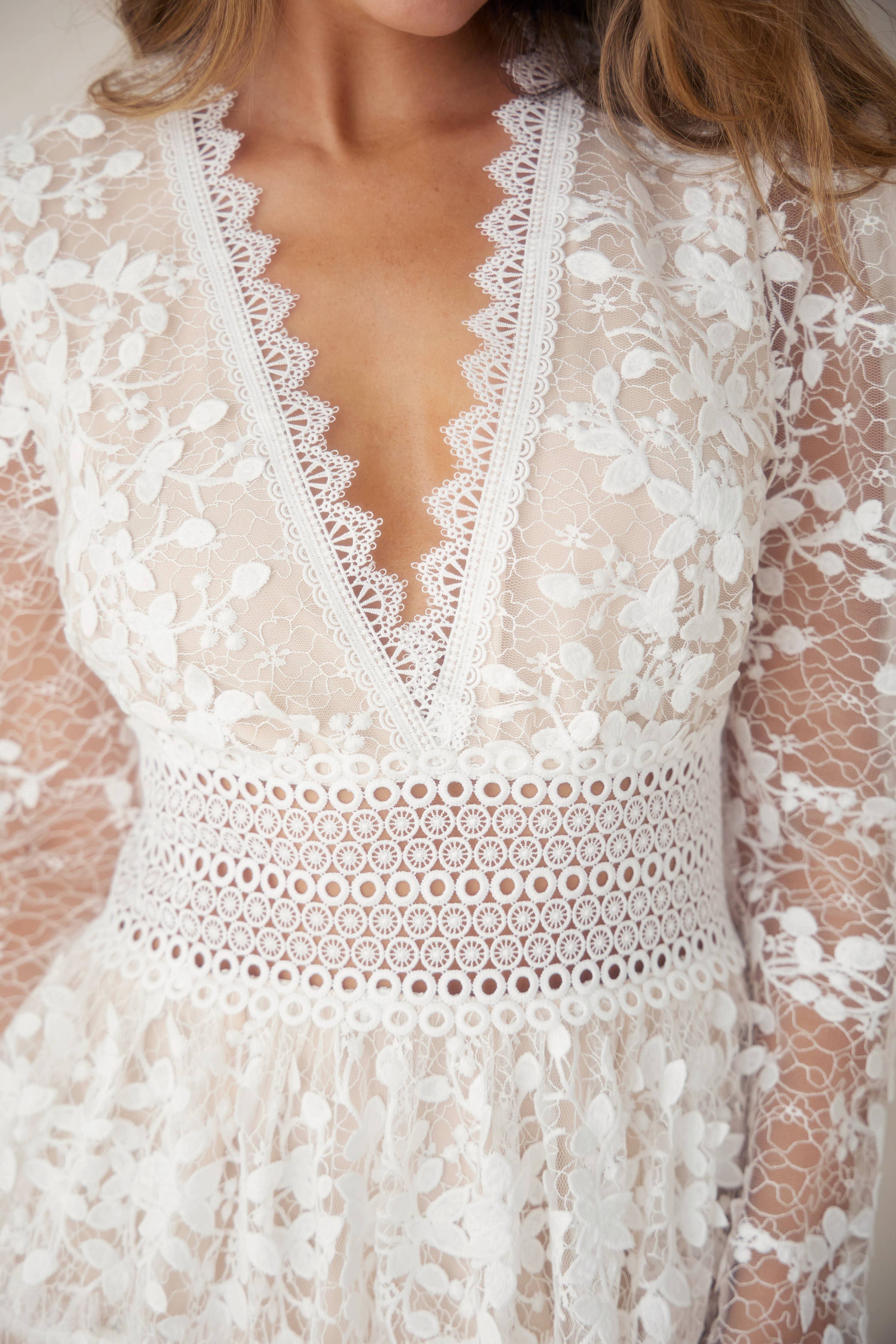 Floral white embroidered lace mini dress with deep V neckline and crochet lace waistband, perfect for resort wear and summer collection.