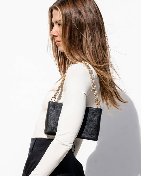 Model showcasing black handbag with gold chain strap, perfect for designer handbags and exclusive women's fashion.