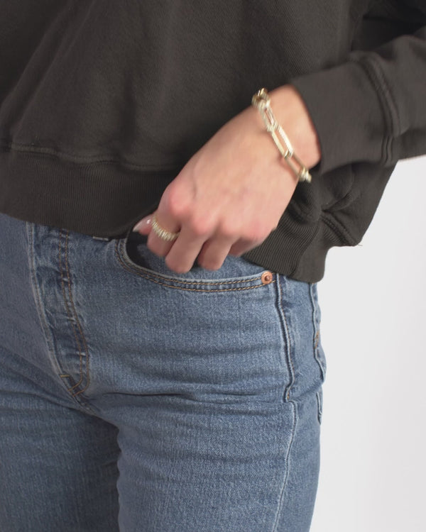 Woman wearing Carrie Pavé Chain Link Bracelet with denim jeans and a dark sweatshirt, showcasing women's boutique jewelry collection.
