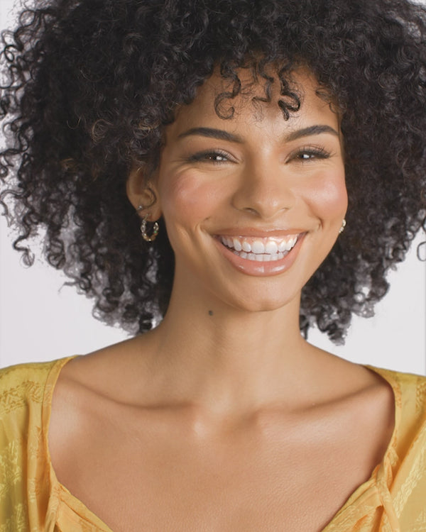 Smiling woman wearing Isla Hoops earrings, showcasing summer collection boutique styles and women's jewelry.