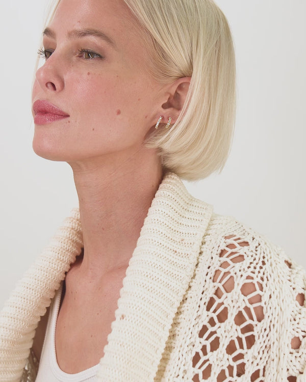 Stylish model wearing They're So Cute Huggie Earrings with crochet cardigan; perfect for women's jewelry summer collection.